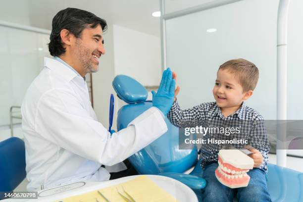 niño feliz resaltando a su dentista mientras sostiene dentaduras postizas - odontopediatría fotografías e imágenes de stock