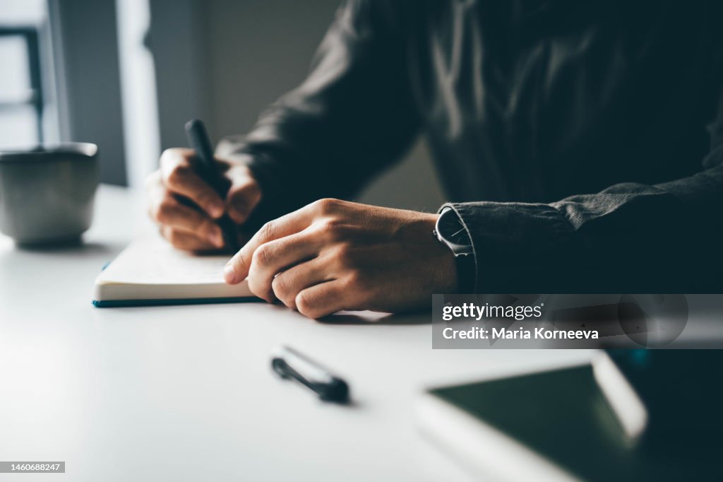 Close-up businessman writing and drawing in notebook.