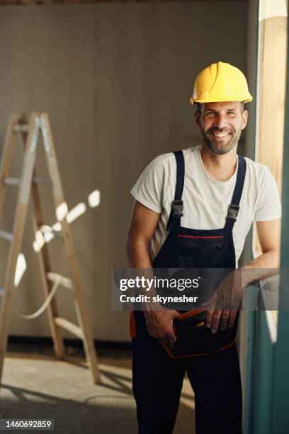 happy manual worker by the window frame at construction site - windowframe stockfoto's en -beelden