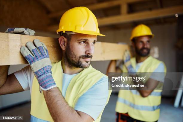 trabajadores manuales que llevan tablones de madera en el sitio de construcción. - albañil fotografías e imágenes de stock