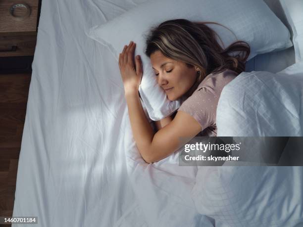 relaxed woman taking a nap in a bed. - serene person stock pictures, royalty-free photos & images