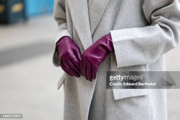 Emilie Joseph wears a pale gray long oversized coat, purple shiny leather gloves , during a street style fashion photo session, in the streets of...