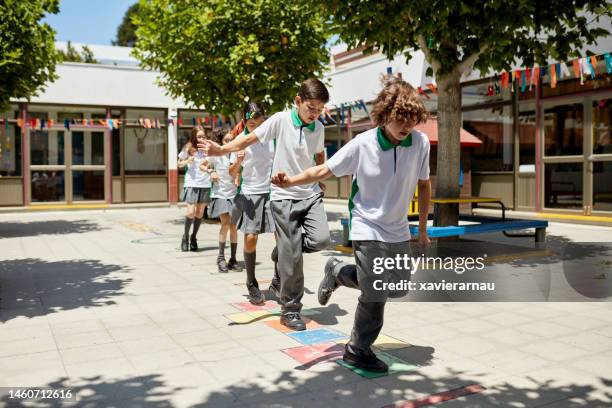 boys and girls playing hopscotch in sunny schoolyard - hopscotch stock pictures, royalty-free photos & images