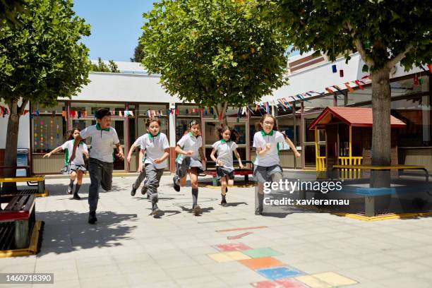 young boys and girls racing across schoolyard - basisschoolgebouw stockfoto's en -beelden