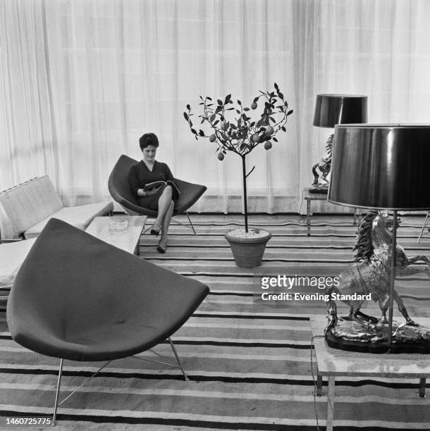 Woman sitting in one of two triangular lounge chairs at the Annual Furniture Exhibition at Earls Court in London on February 6th, 1961.