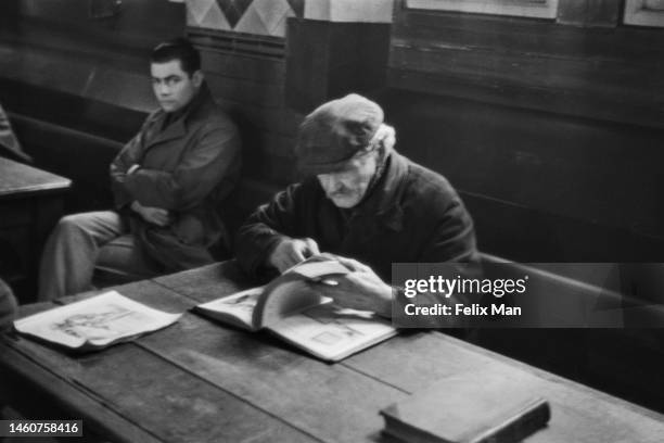 Man sits at a table looking through a book, Cardiff. Original Publication: Picture Post - 104 - Cardiff - pub. 1939