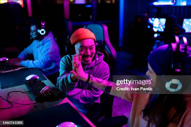felice giocatore asiatico che si congratula con il suo amico per aver vinto negli esport. - sport elettronici foto e immagini stock