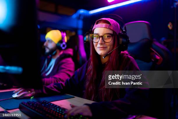smiling woman playing video games over pc in entertainment club. - gaming station stock pictures, royalty-free photos & images
