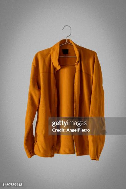 a mustard fleece jacket hanging on a hanger. - brown jacket foto e immagini stock