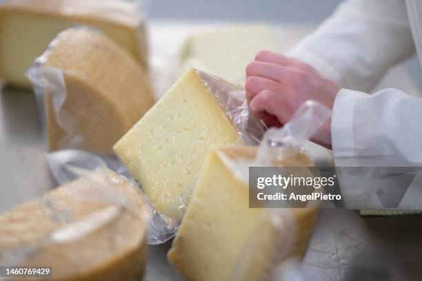 a woman packages portions of cheese in a manchego cheese factory. - cheese stock pictures, royalty-free photos & images