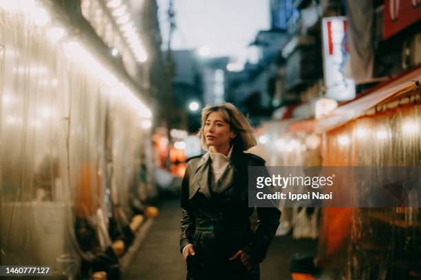 woman walking through tokyo backstreet at night in winter - tokyo japan night alley stock pictures, royalty-free photos & images