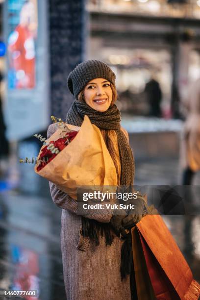 a woman carrying a bouquet of roses - winter woman showing stock pictures, royalty-free photos & images