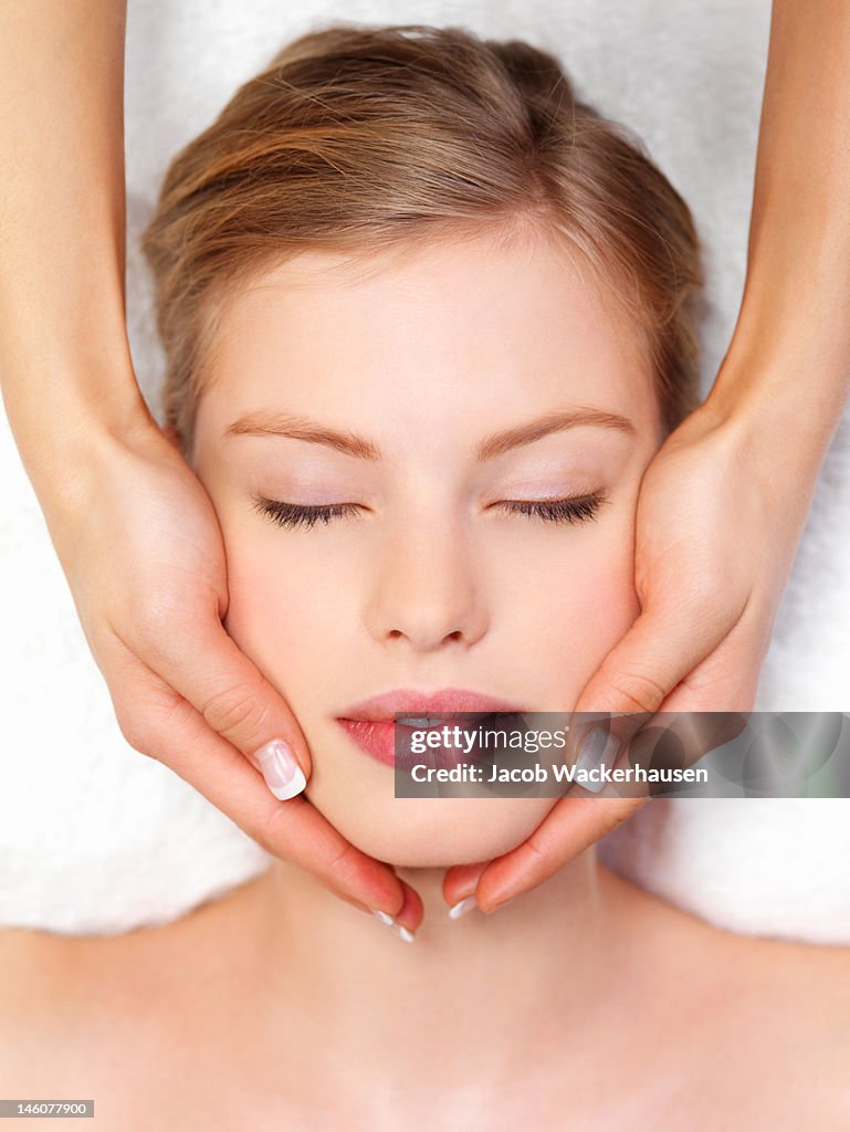 Close-up of young woman receiving facial massage at day spa