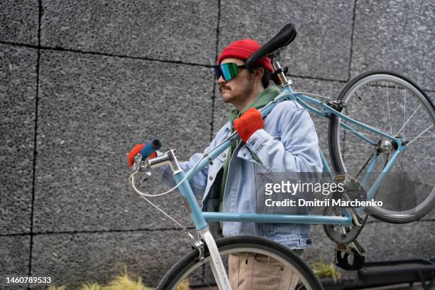 confident man with mustache carries bicycle on shoulder after breakdown or need to replace parts - georgian man stock pictures, royalty-free photos & images