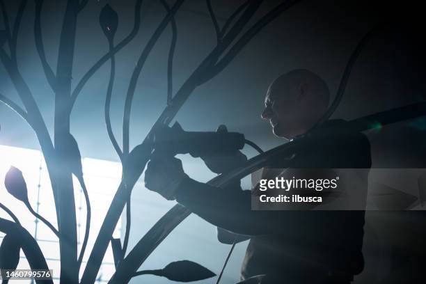 blacksmith artist working in his smithy studio creating a gate-tree - art smith stock pictures, royalty-free photos & images