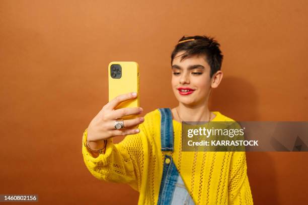 child feeling feminine and using a smart phone on brown background. gender confusion in adolescence. - hesitant to dance stock pictures, royalty-free photos & images