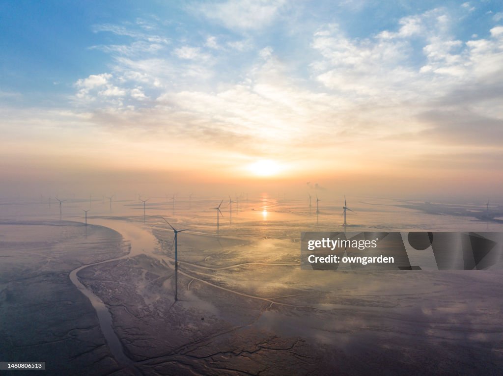 Big Wind turbine farm in mudflats at sunrise