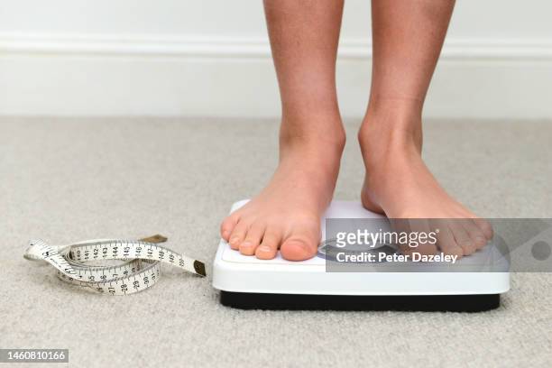boy on scales with tape measure - childhood obesity stock pictures, royalty-free photos & images