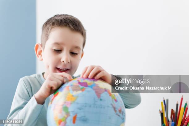 caucasian boy holds globe white background - multilingual stock pictures, royalty-free photos & images