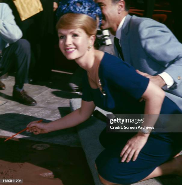 Debbie Reynolds signing her name at Grauman's Chinese Theatre by the Hollywood Walk of Fame, 1965.