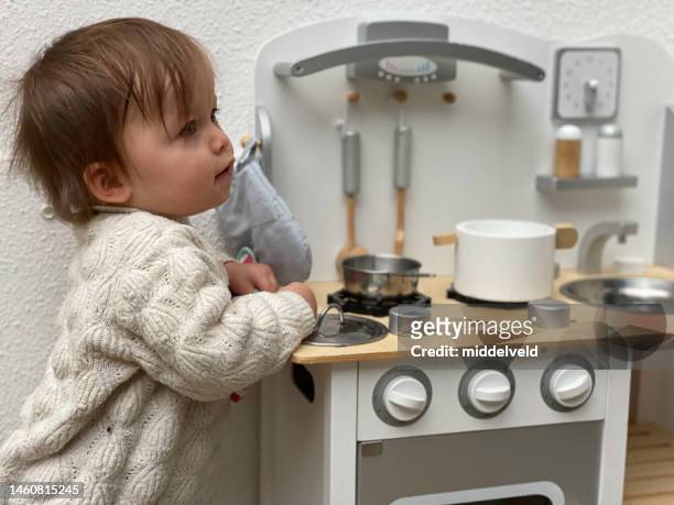 cute toddler girl playing with kitchen - winter baby stockfoto's en -beelden
