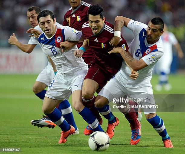 Venezuelan Nicolas Fedor is marked by Chilean Jose Rojas and Arturo Vidal during their Brazil 2014 FIFA World Cup South American qualifier match held...