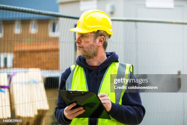 construction worker examining documents on clipboard - superior council stock pictures, royalty-free photos & images