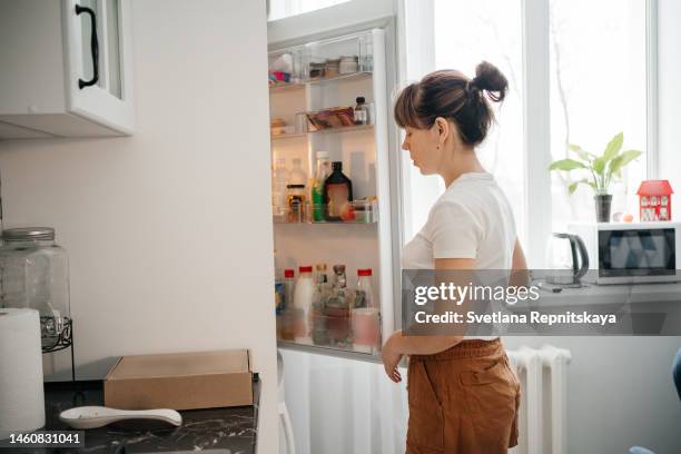 tired mom opened the fridge - congelador fotografías e imágenes de stock