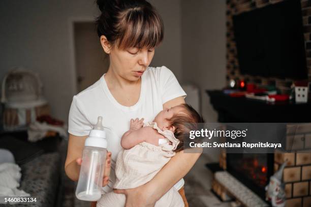 mother feeding her newborn baby formula from a bottle - milchpulver stock-fotos und bilder