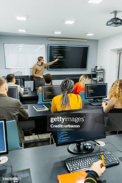 junge männliche lehrerin, die eine programmierklasse unterrichtet - dozent mann vortrag stock-fotos und bilder