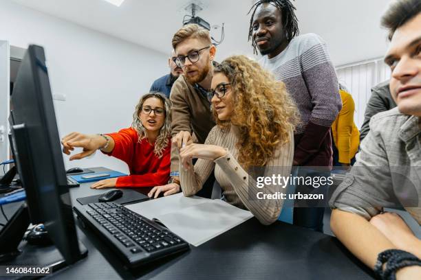 estudiantes trabajando juntos para resolver un problema en la clase de programación - laboratorio de ordenadores fotografías e imágenes de stock