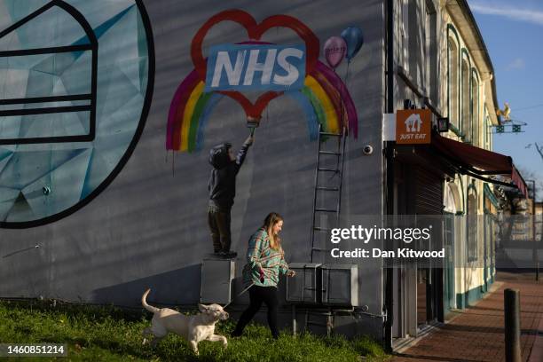 Woman and her dog walk past a Banksy inspired sign supporting the NHS on January 30, 2023 in Grays, United Kingdom. January 31, 2023 marks the 3rd...