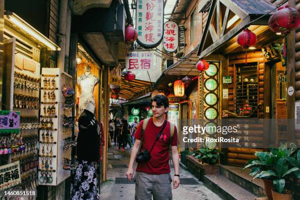 tourist with camera walking through the market streets of jiufen in taiwan - taipei taiwan stock pictures, royalty-free photos & images