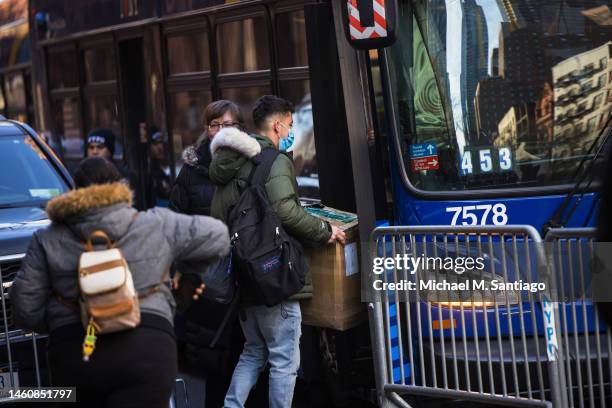 Migrants carry their belongings to a bus after accepting relocation after being evicted from the Watson Hotel on January 30, 2023 in New York City....