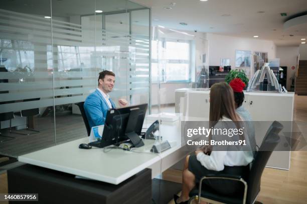 car dealer with customers at desk in showroom - rental assistance stock pictures, royalty-free photos & images