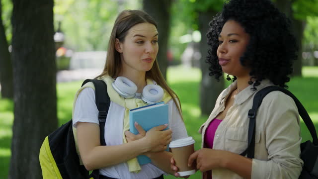 Cheerful young woman student giving high five to best friend, students greeting