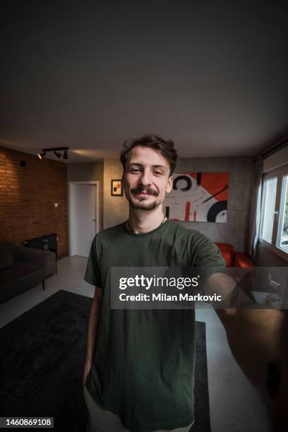 handsome caucasian man with mustache taking self portrait at home in his living room - selfie male stock pictures, royalty-free photos & images