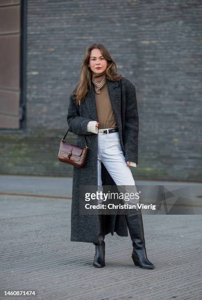 Therese Hellström wears white pants, black knee high boots, grey coat, burgundy bag, brown scarf, jumper outside Herskind during the Copenhagen...