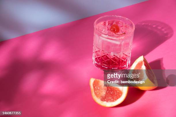 cocktail-drinkglas mit rosa pomelo und kirsche - gin stock-fotos und bilder