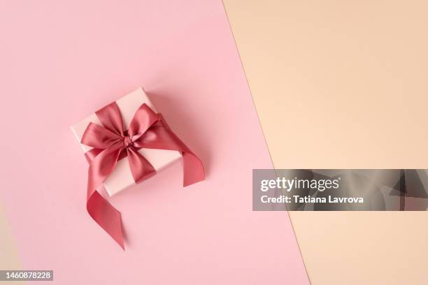 gift box with satin magenta ribbon on festive pink paper background with copy space. valentines day, international women day, mothers day concept - opening gift stockfoto's en -beelden