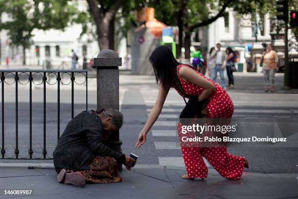 Woman gives alms to a homeless in Cibeles Square on June 9, 2012 in Madrid, Spain. Despite the severe budget cuts that Spanish Government is making,...