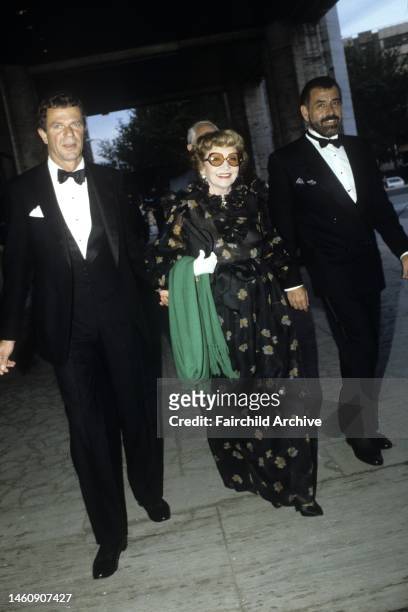 Claudette Colbert flanked by men attends the annual New York City Ballet Spring Gala on June 3, 1983 in New York.