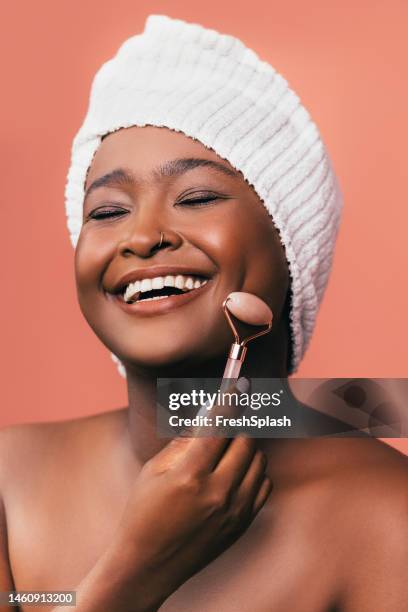 a happy beautiful woman wrapped in a towel relaxing after taking a shower with her eyes closed - cheek stock pictures, royalty-free photos & images
