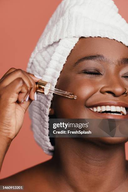 eine glückliche, schöne frau, eingewickelt in ein handtuch, die sich mit geschlossenen augen um ihre haut kümmert - african american women wet stock-fotos und bilder