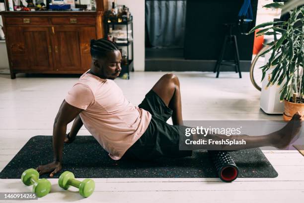 ein ernsthafter mann auf yogamatte, der sein tägliches training zu hause macht - black men feet stock-fotos und bilder