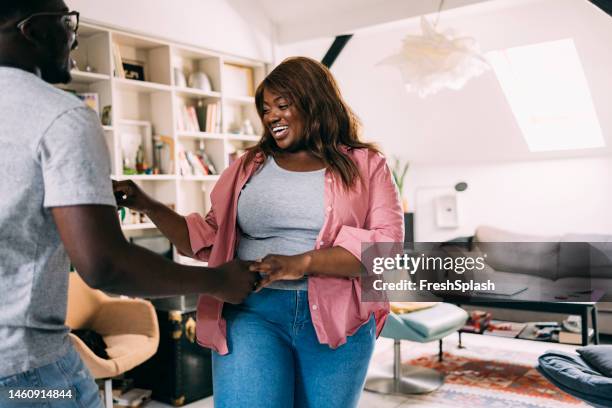 a happy overweight beautiful woman dancing with her boyfriend in the living room - fat woman dancing stockfoto's en -beelden