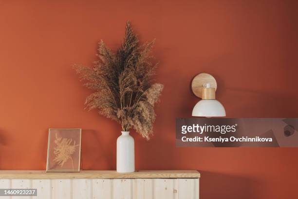 high pampas grass in a vase against a terracotta-red wooden cabinet with stacked doors like blinds. pampas grass in the interior, boho style. minimalism - wohngebäude innenansicht stock-fotos und bilder