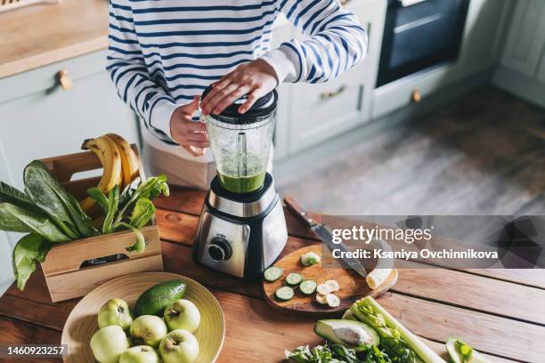 healthy eating, cooking, vegetarian food, dieting and people concept - close up of young woman with blender and green vegetables making detox shake or smoothie at home - avocado smoothie stock pictures, royalty-free photos & images