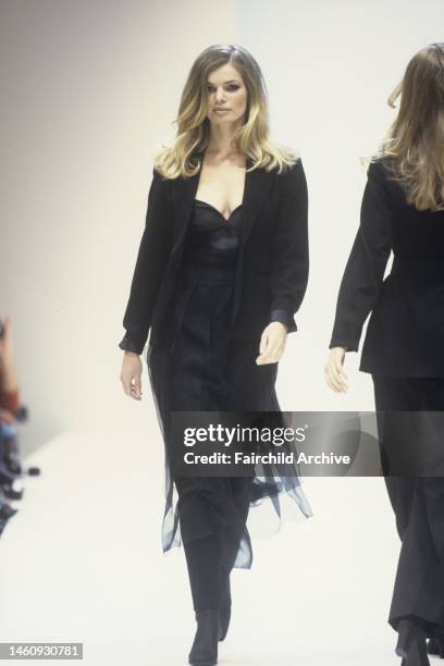 Also appeared in WWD 4/29/1992 p.8; A model wears a sweet-heart necklined black dress with a tulle skirt over black slacks with a tailored black...