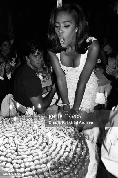 Naomi Campbell blowing out candles on her birthday cake.